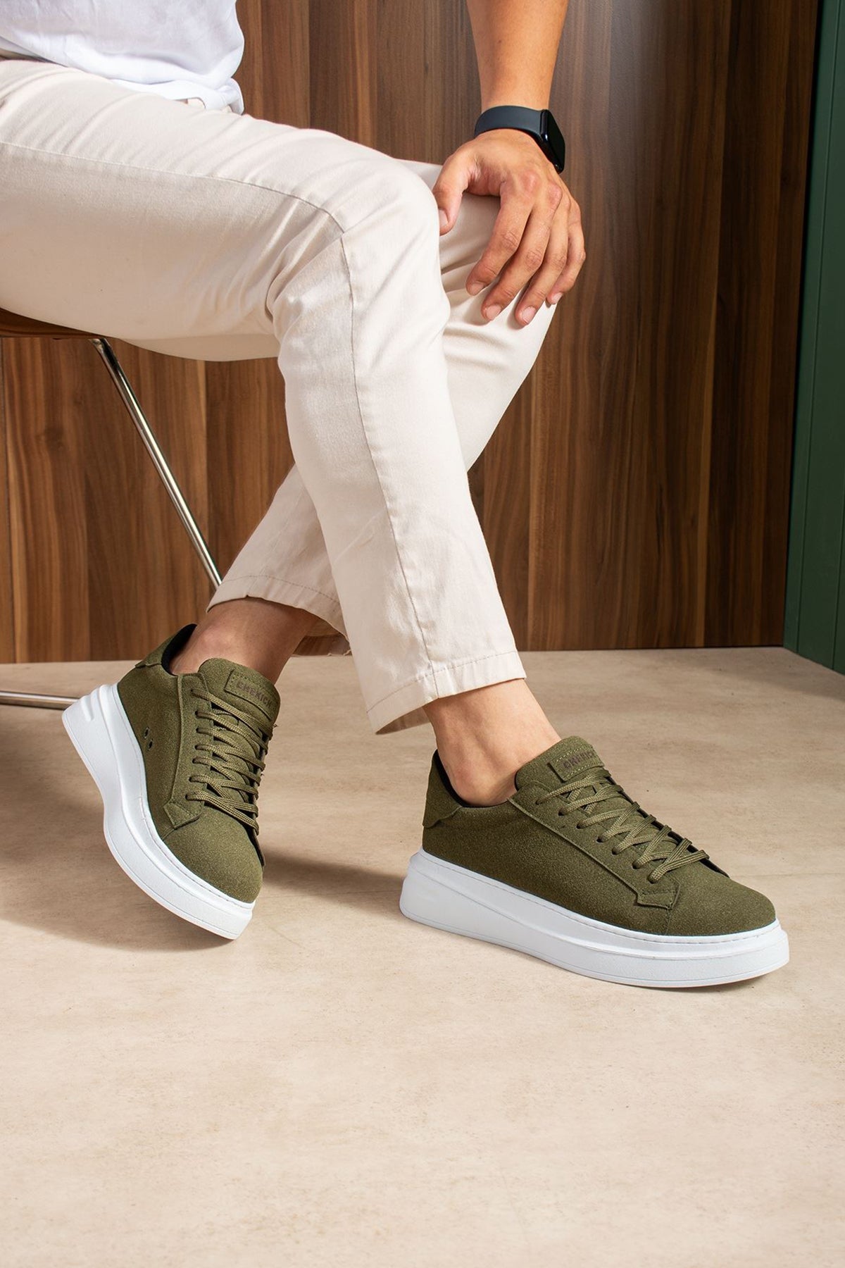 Men's olive suede low-top sneakers, lace-up, white soles, close side step pose