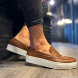 Men's tan suede loafers with strap detailing and white rubber sole, angled side view