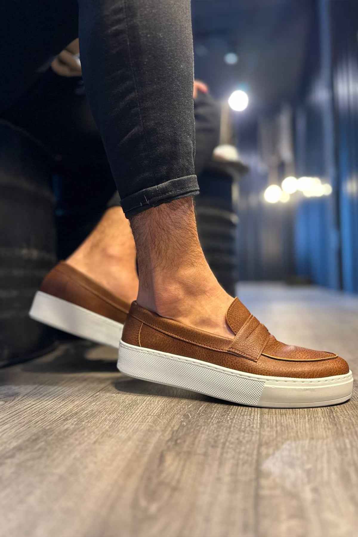 Men's tan suede loafers with strap detailing and white rubber sole, angled side view