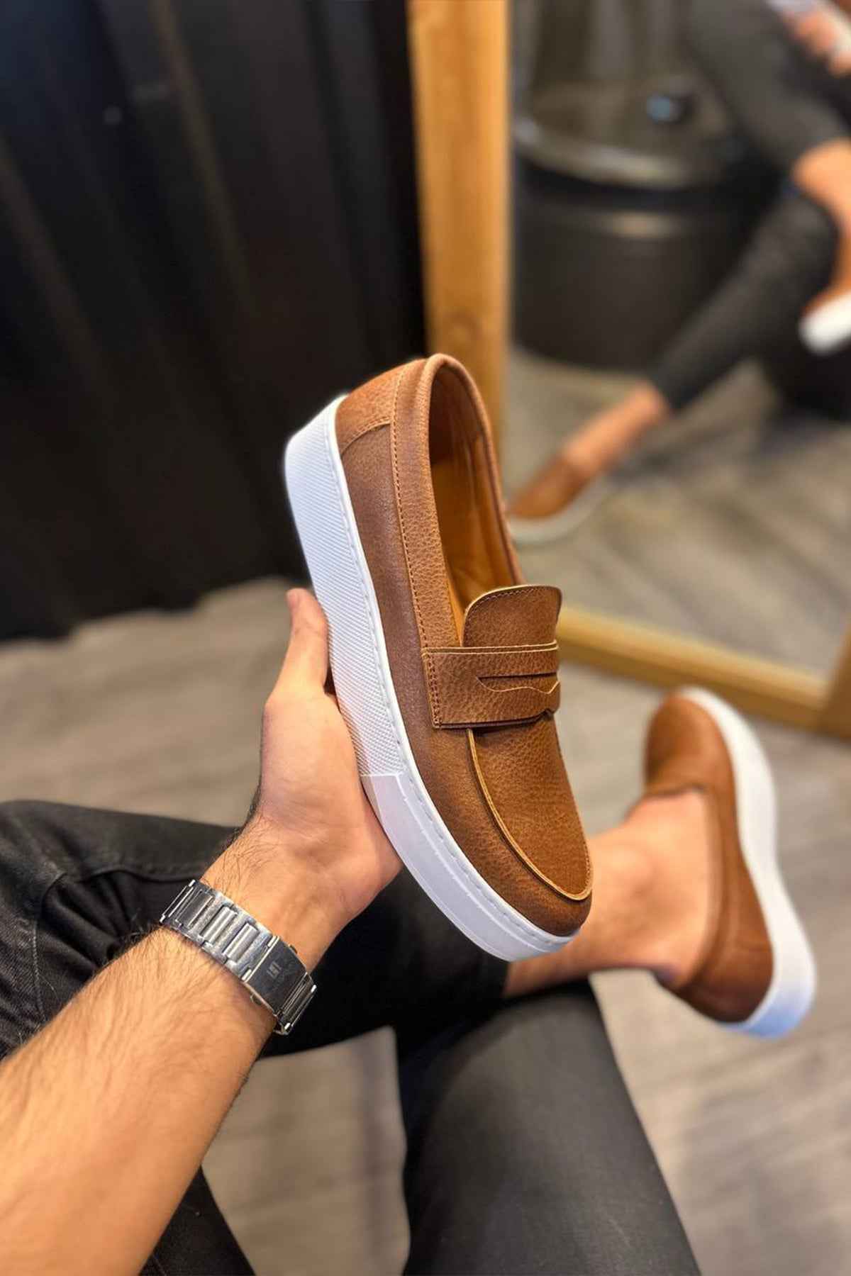 Tan suede loafer with strap and white sole, shown on foot with dark jeans
