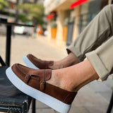 Men's tan casual loafers on foot, buckle strap and white rubber sole