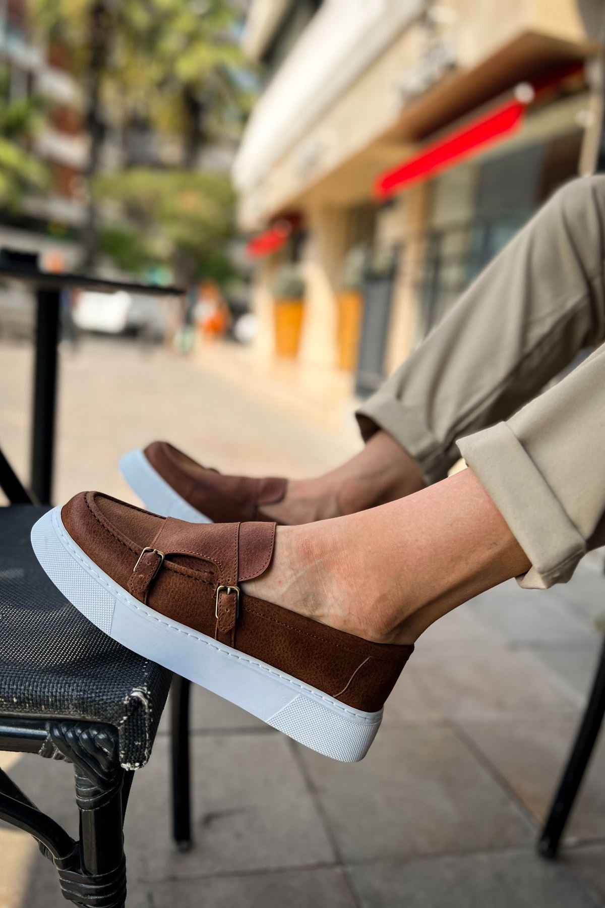 Men's tan casual loafers on foot, buckle strap and white rubber sole