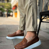 Brown slip-on loafers with white sole, front-side view, low profile.