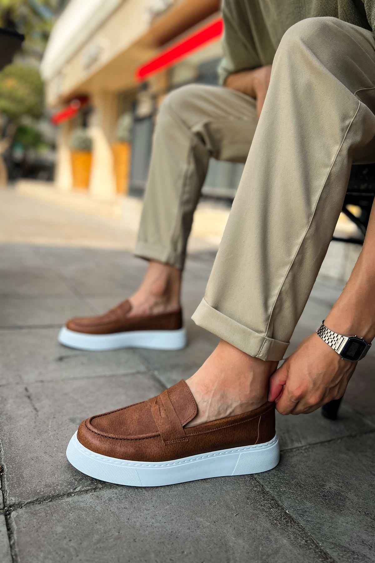 Brown slip-on loafers with white rubber sole, detailed vamp seam.