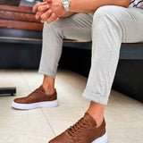 Tan lace-up sneakers with white soles and rounded toe, low-top profile