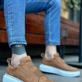 Men's tan suede slip-on sneakers with light blue rubber sole, front view