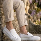 Pair of white men's loafers with strap closure and stitched toe apron