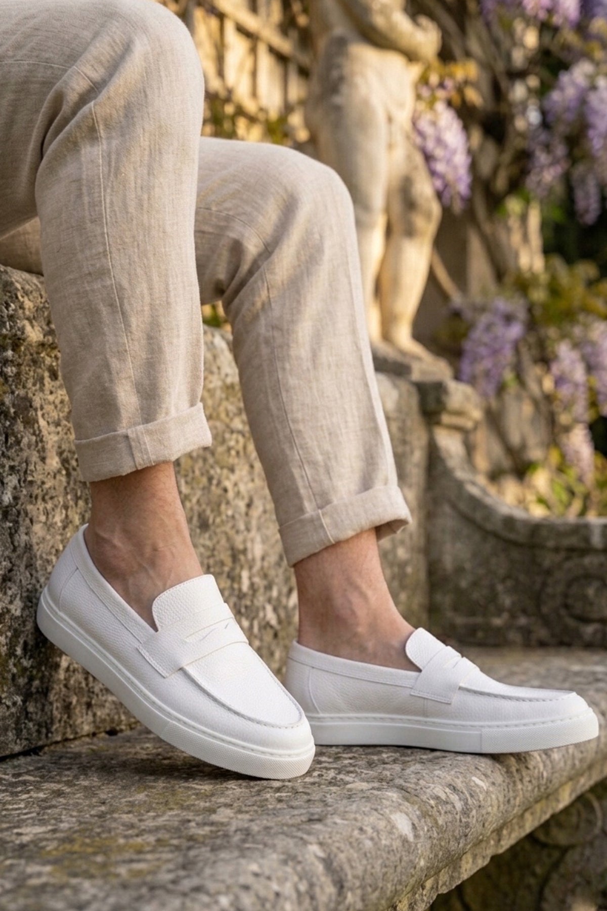 Pair of white men's loafers with strap closure and stitched toe apron