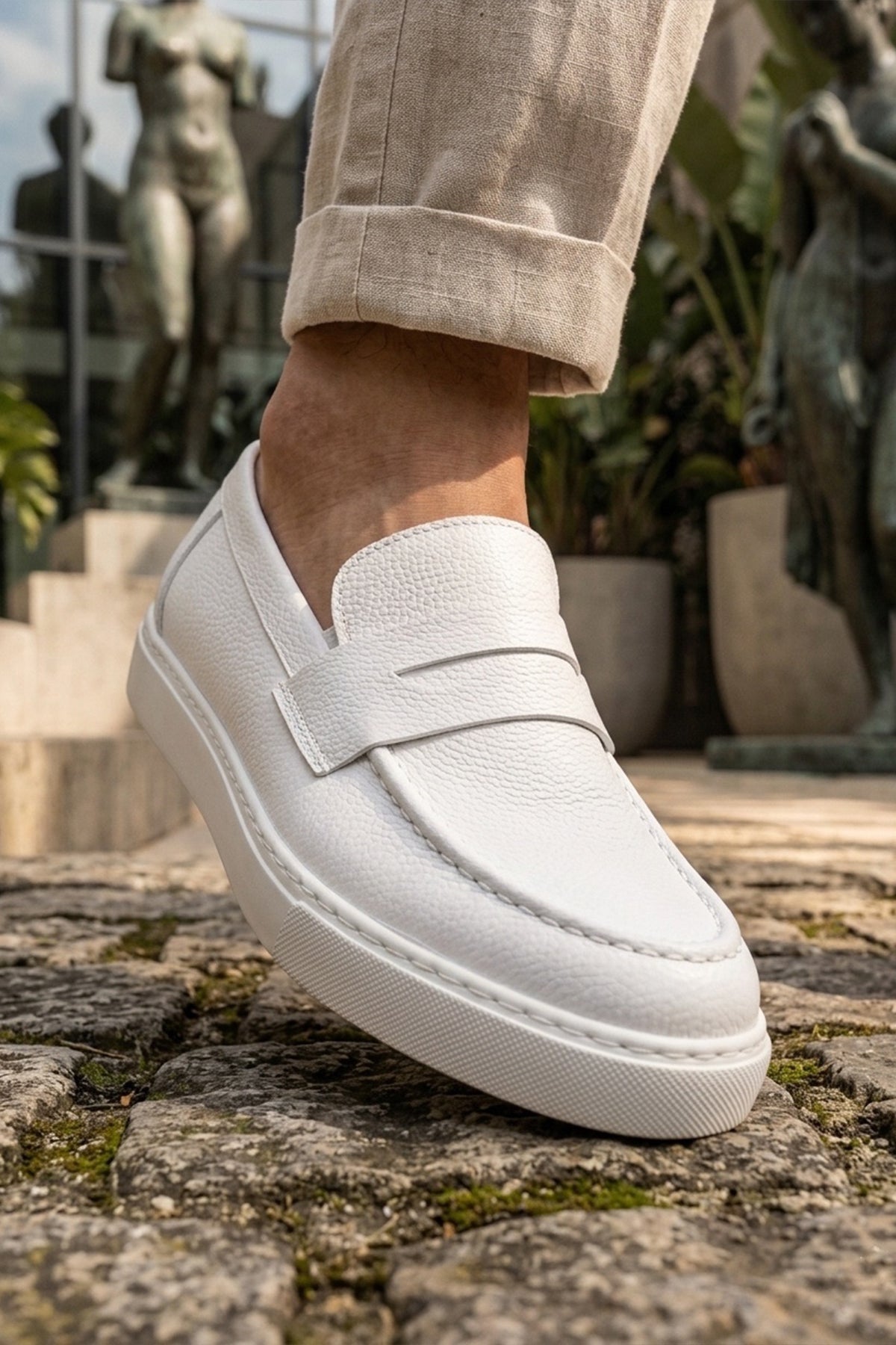 White leather-look men's loafers with strap, curved stitching, and thick sole