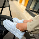 Men's casual white low-top sneakers, side view with lace and stitching