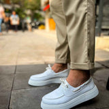 Men's casual white low-top sneakers on pavement, front quarter view