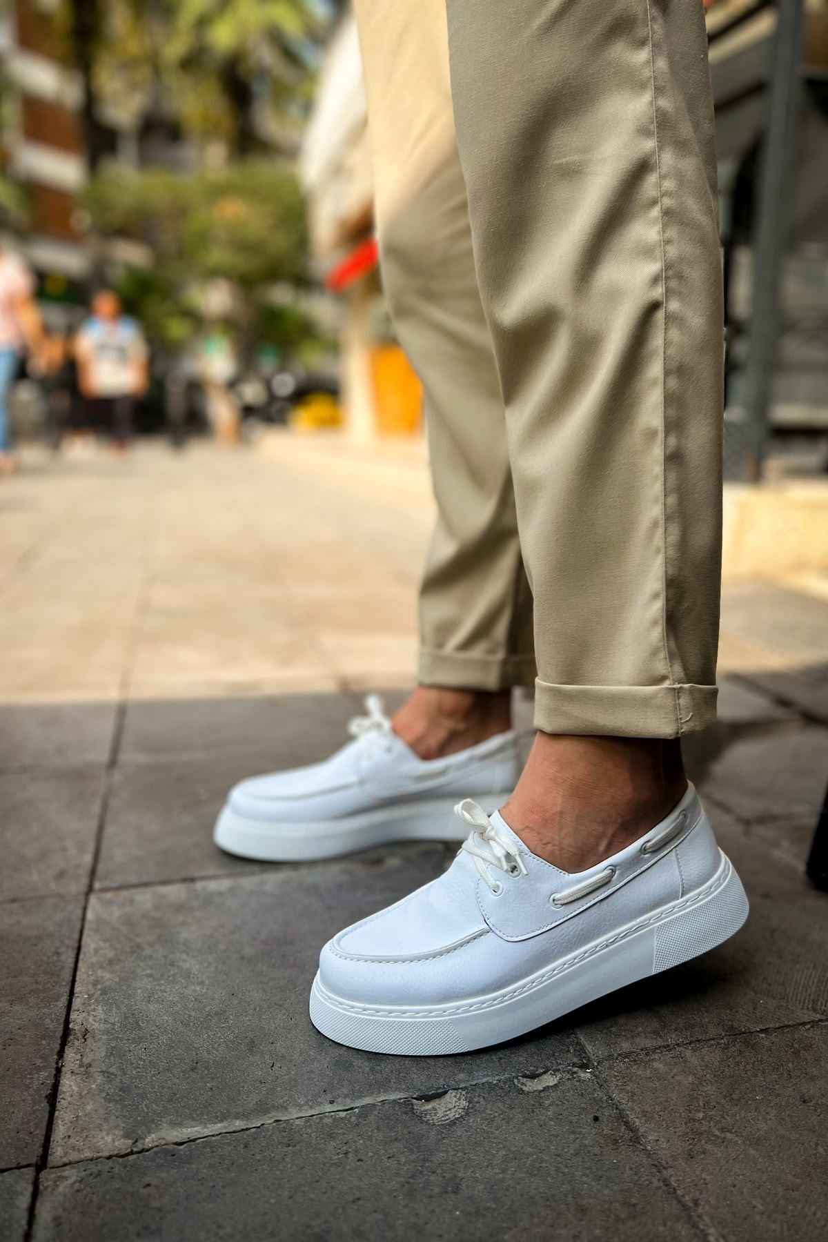 Men's casual white low-top sneakers on pavement, front quarter view