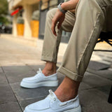 Men's casual white low-top sneakers on pavement, front quarter view