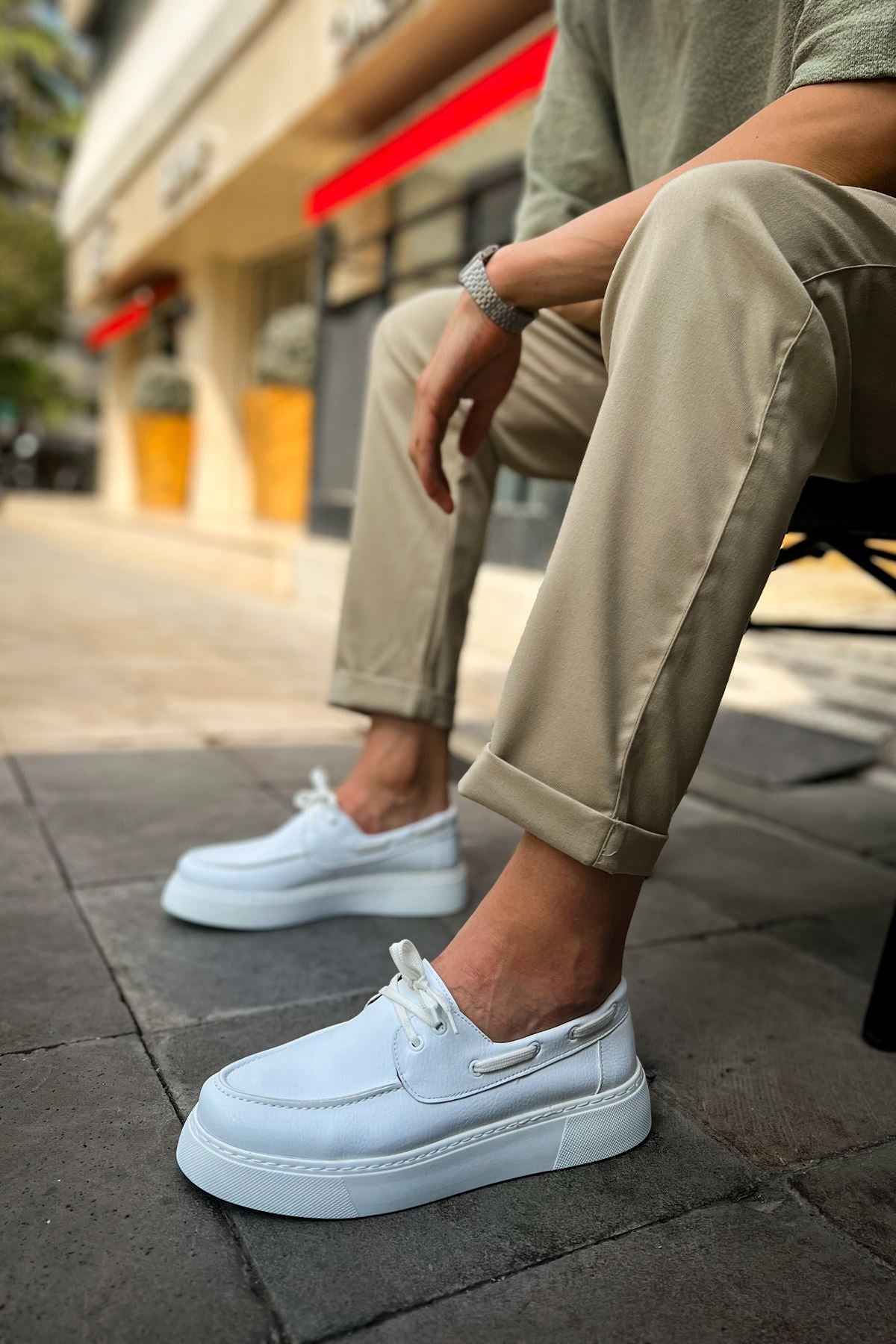 Men's casual white low-top sneakers on pavement, front quarter view