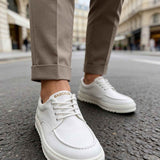 Men's casual white lace-up shoes with textured sole, worn with cuffed pants