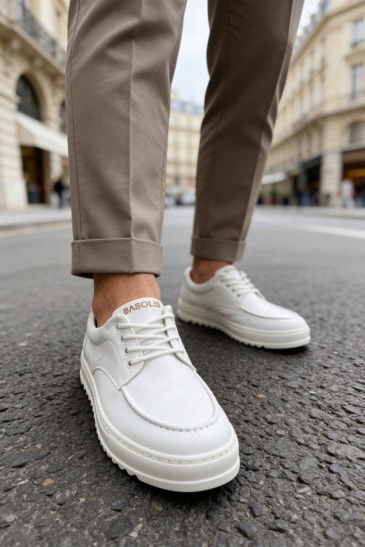 Men's casual white lace-up shoes with textured sole, worn with cuffed pants