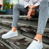 White lace-up sneakers with brown heel tab and gum sole