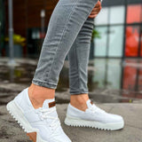 White lace-up sneakers with brown logo patch and rubber sole
