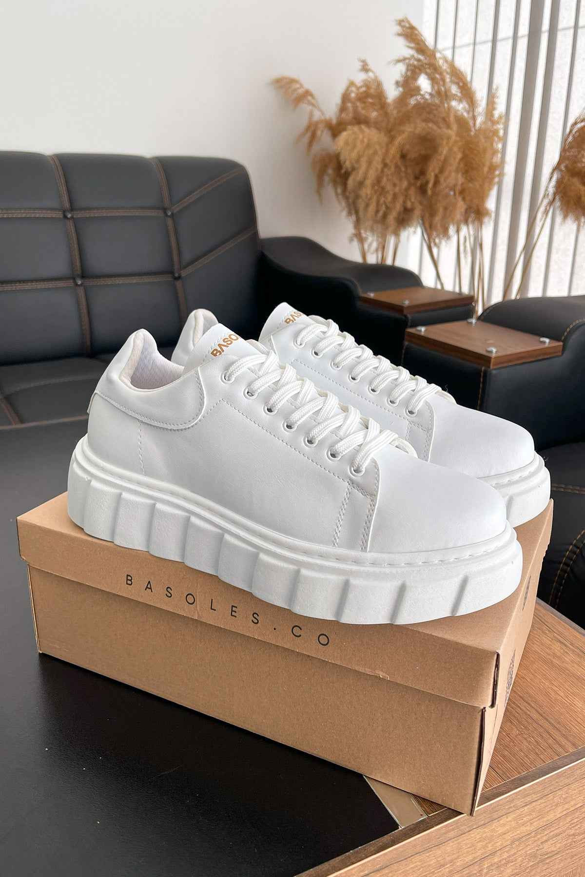 White lace-up low-top sneakers with chunky platform sole, on display box.