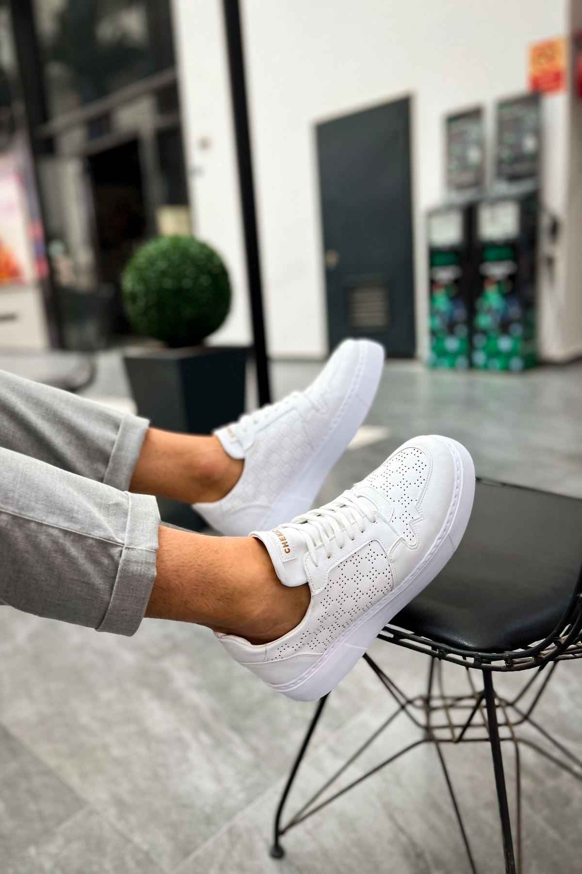 Men's white low-top sneakers on angled foot, lace-up with side texture