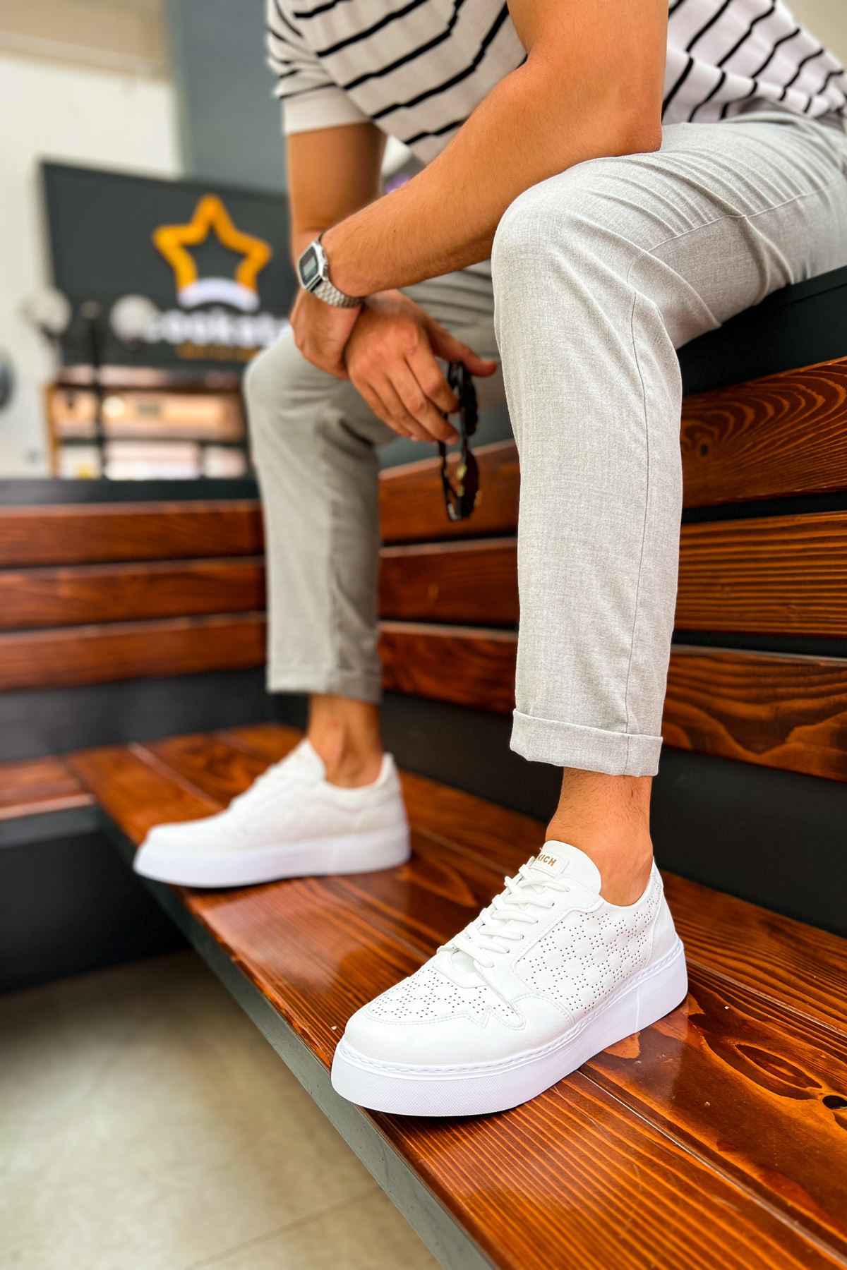 Men's white casual sneakers on wooden ledge, lace-up low-top profile