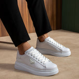 Men's white low-top lace-up sneakers with side logo patch, worn with dark pants