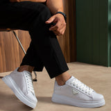 Men's white low-top sneakers with lace-up front and side patch, standing stance