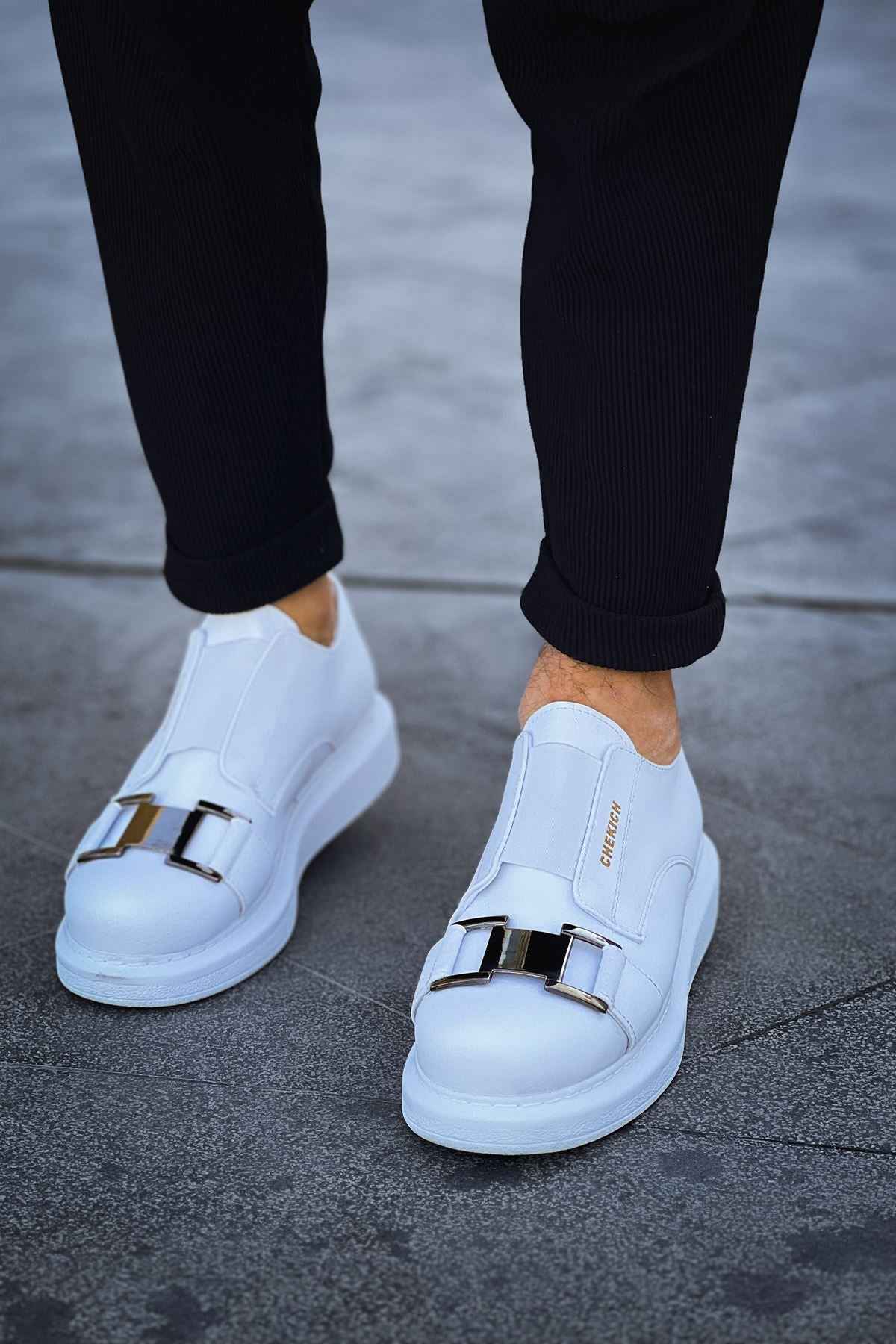 Men's white sneakers, front view, double strap buckle detail and rubber sole.