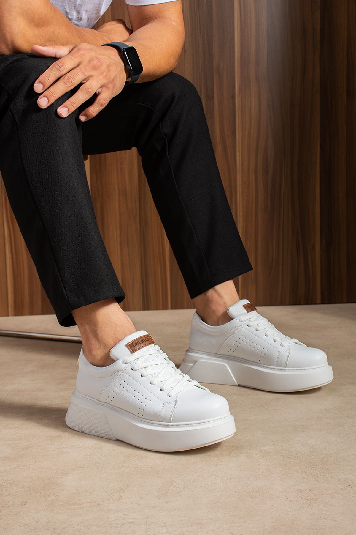White sneakers on feet, lace-up design with tan heel tab and padded collar
