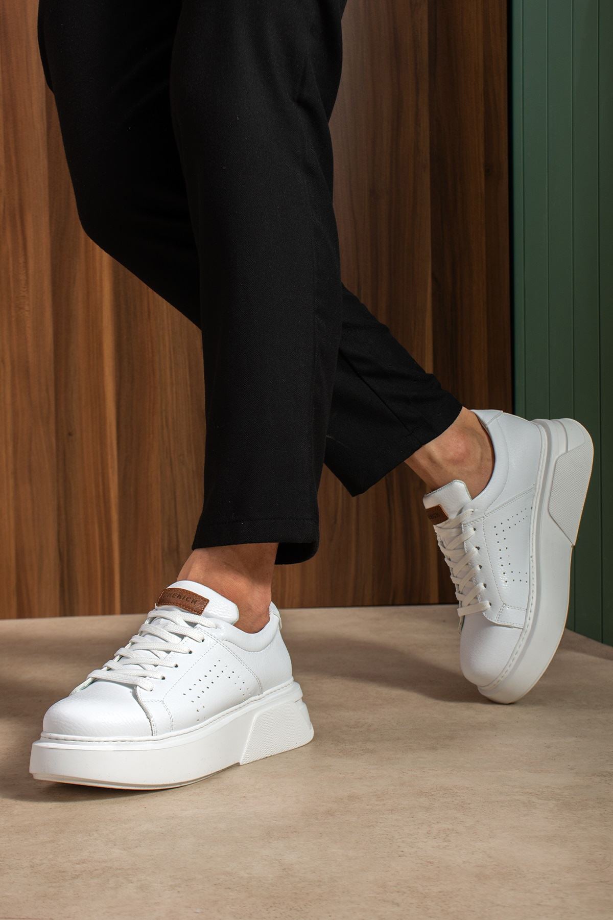 White sneakers with lace-up front, chunky sole, tan heel tab, walking stance