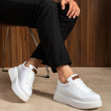 White lace-up sneakers with perforated detailing, tan heel tab and thick sole