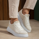 White suede low-top sneakers with lace-up front and light blue rubber sole.