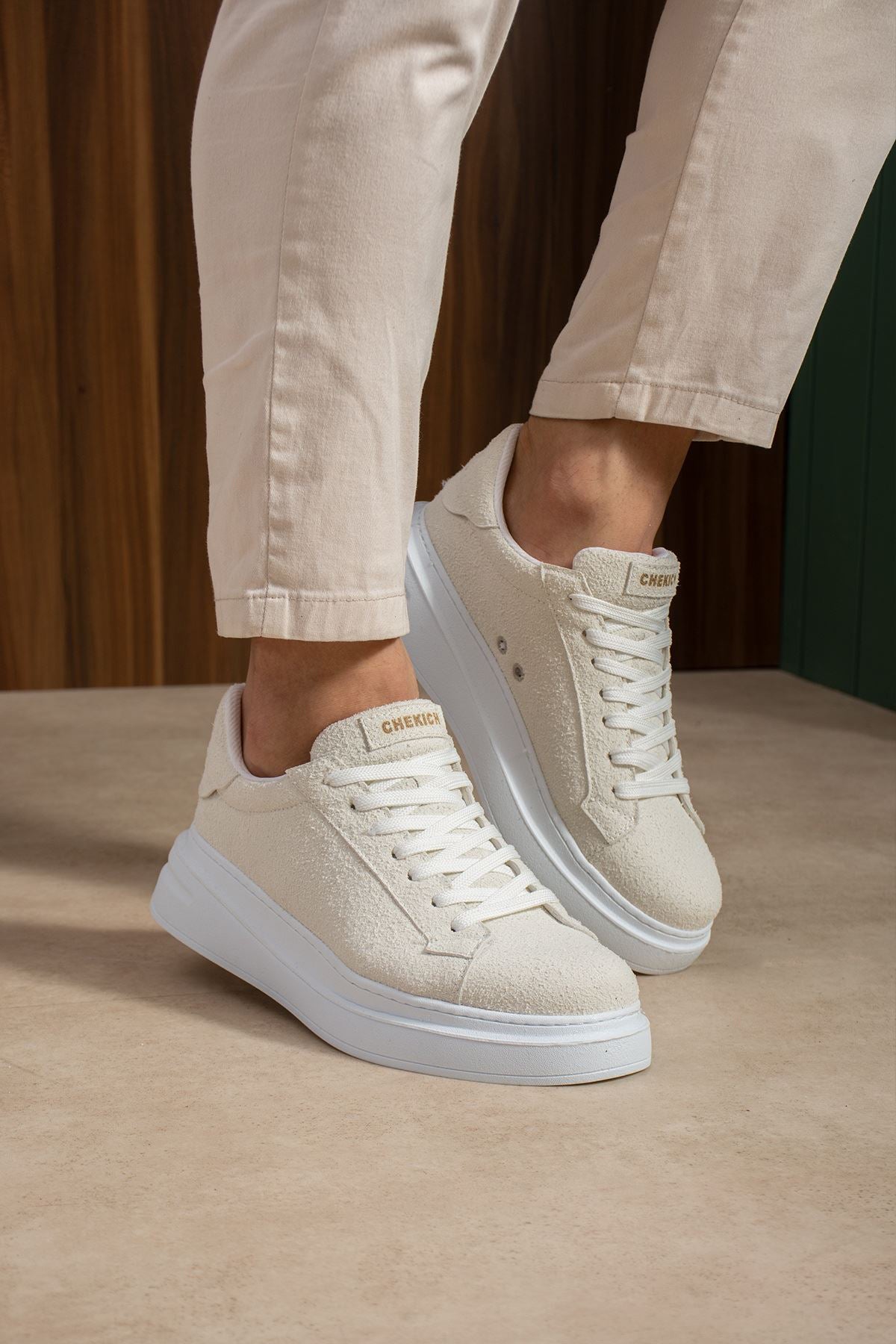 White suede low-top sneakers with lace-up front and light blue rubber sole.