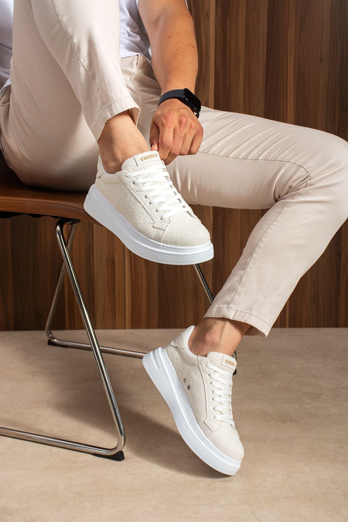 White suede sneakers on model feet, lace-up design and blue-gray platform sole.