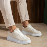 White suede low-top sneakers with lace-up closure and textured side panels.