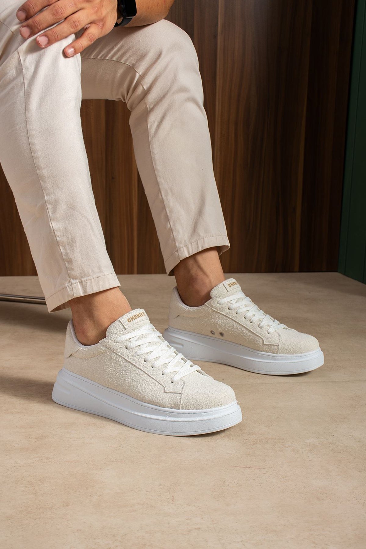 White suede low-top sneakers with lace-up closure and textured side panels.