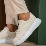 White suede sneakers in profile, lace-up tongue and thick white sole.