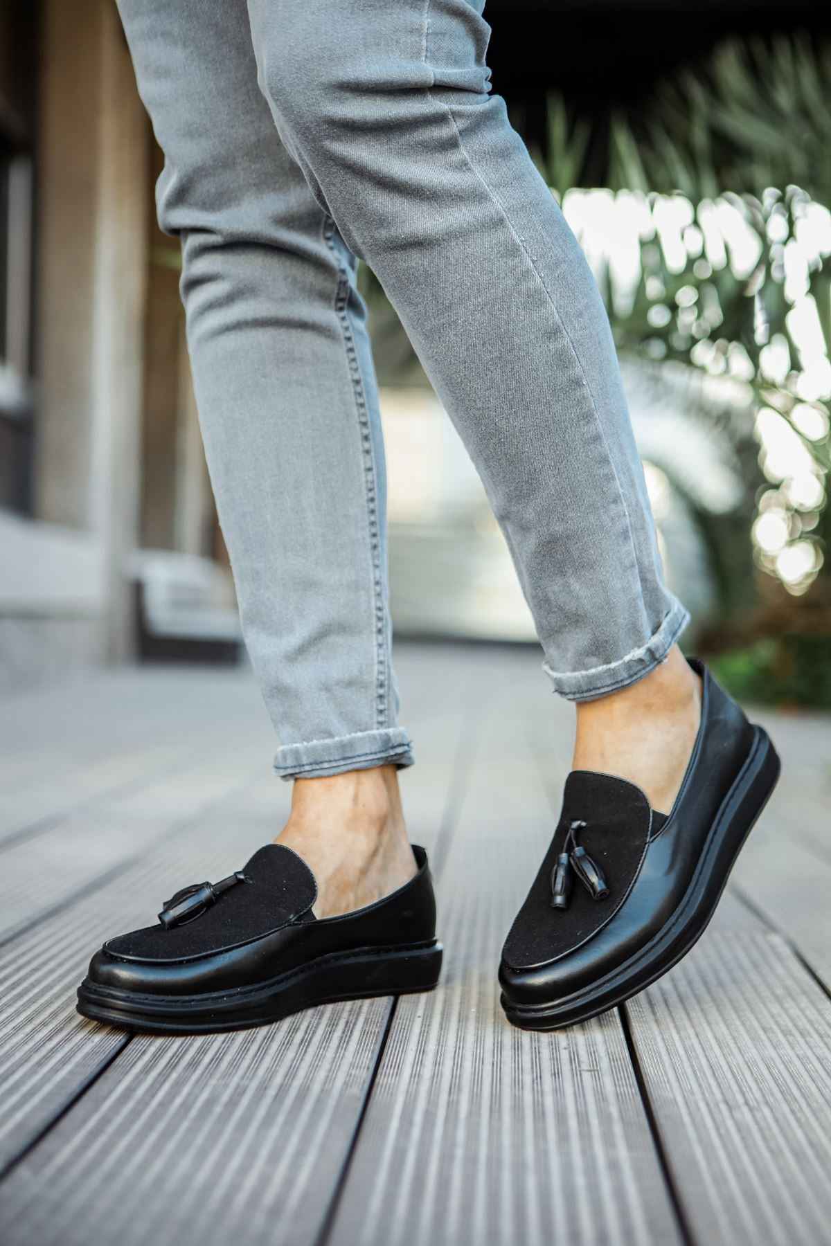 Men's black leather tassel loafers, side view, rounded toe, slip-on style