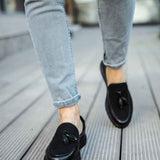 Men's black leather tassel loafers, on foot, rounded toe and low sole