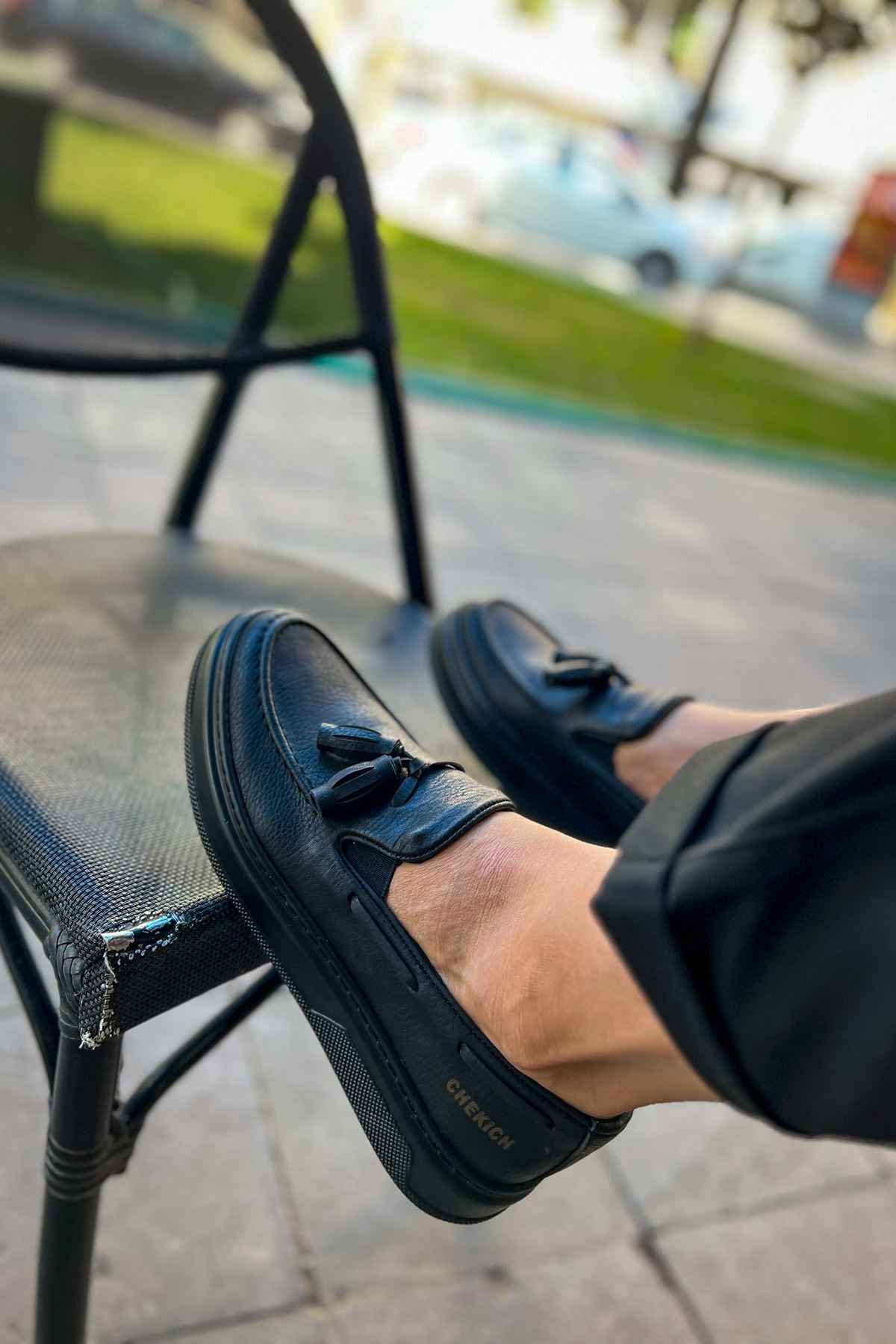 Men's black loafer with tassel detail, front angled view with stitched toe.