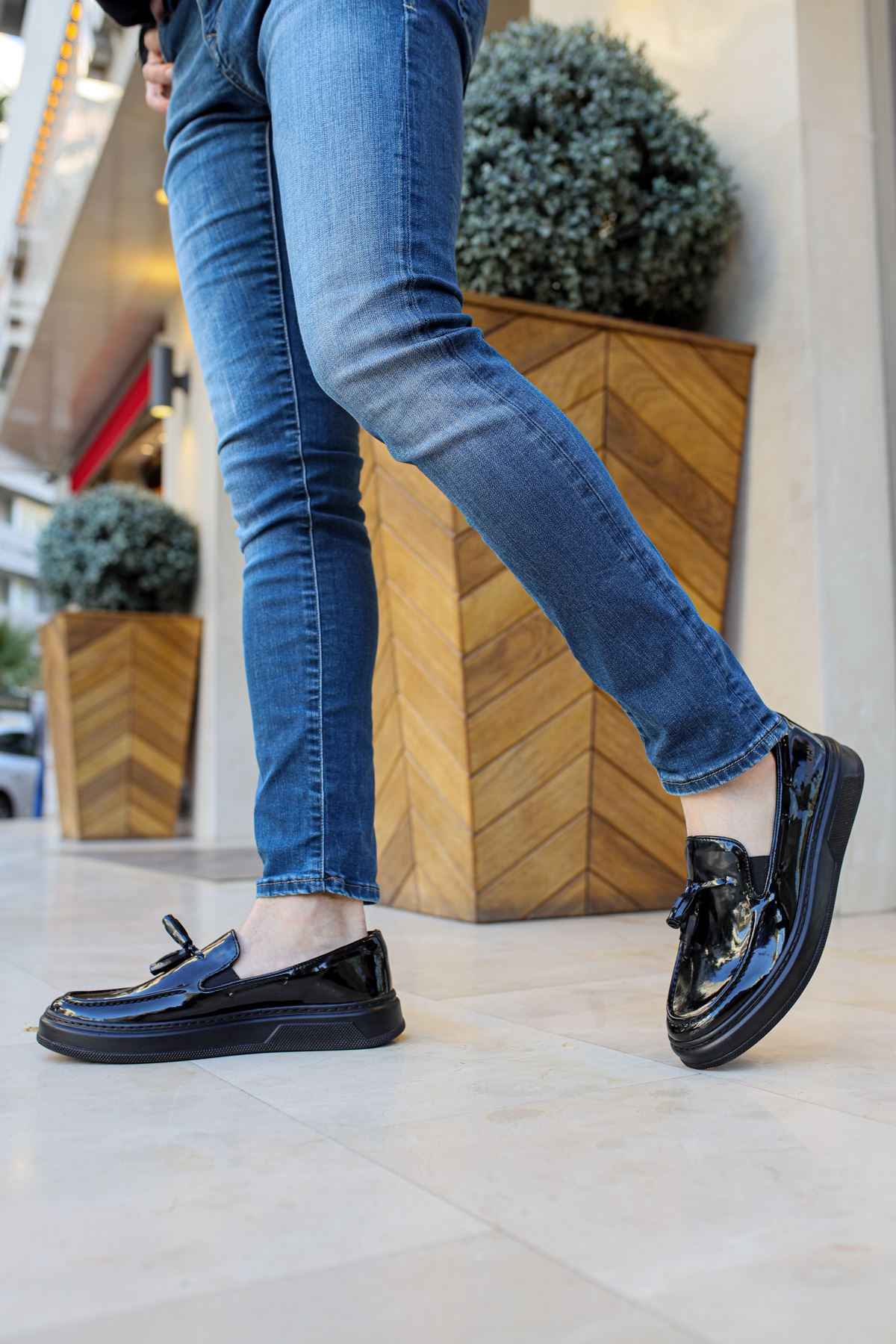 Black patent leather loafer with strap, low sole, and slight heel