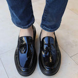Black glossy patent leather loafer with strap detailing and rounded toe