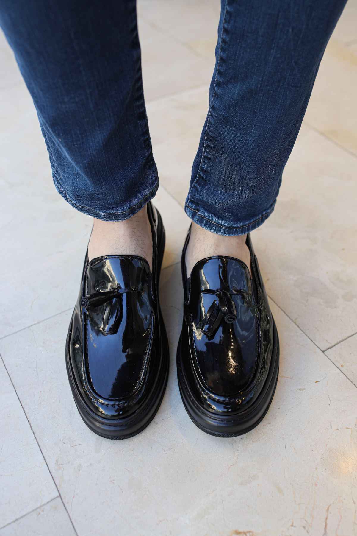 Black glossy patent leather loafer with strap detailing and rounded toe