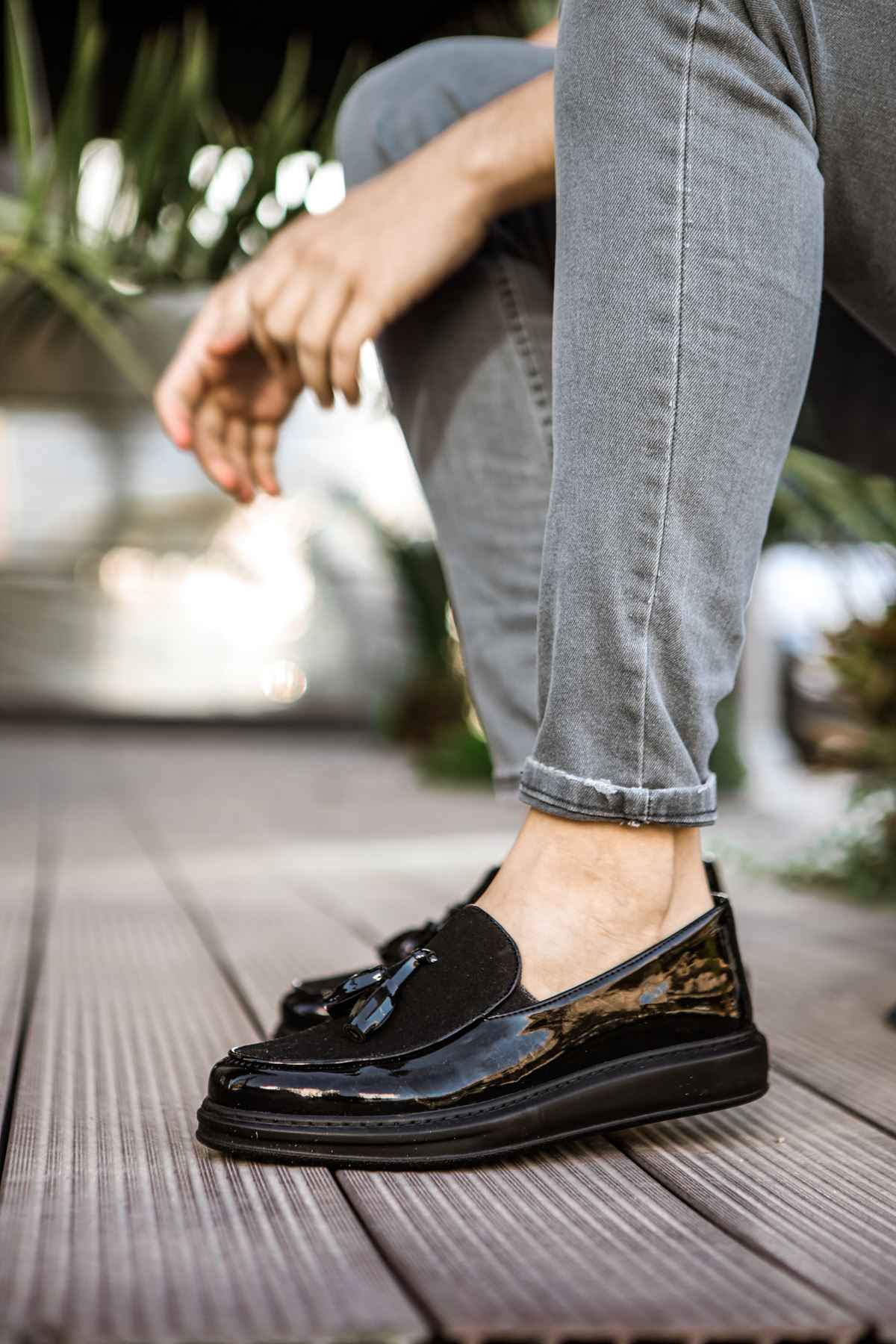 Black patent leather loafer with tassel detail, worn with light blue jeans