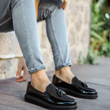 Black patent leather loafers with tassel detail, worn with light blue jeans