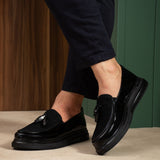 Men's black patent leather tassel loafers, side view with glossy finish
