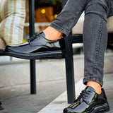 Men's black patent leather lace-up shoes, laces tied, side angle while seated