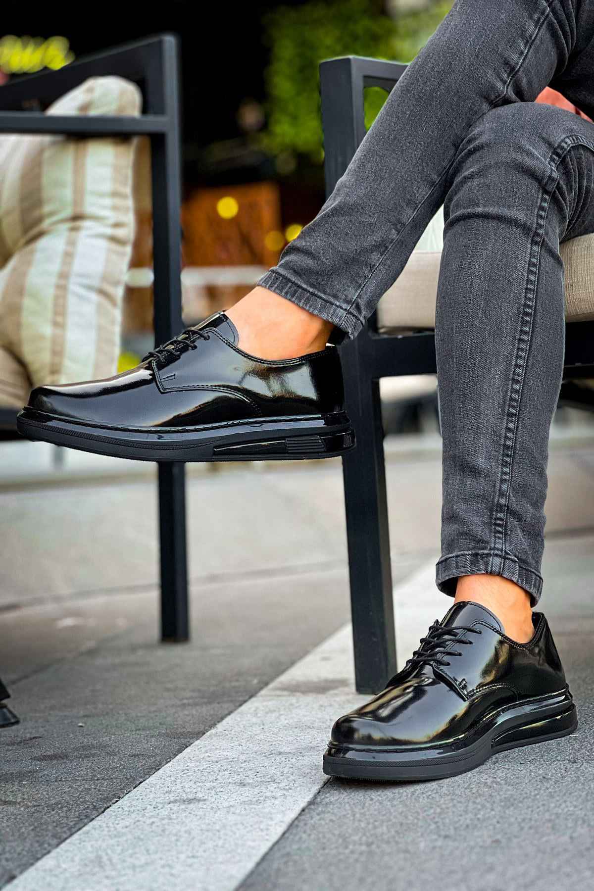 Men's black patent leather lace-up shoes, laces tied, side angle while seated