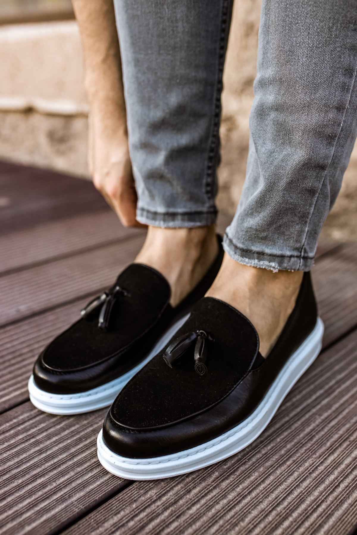 Men's black tassel loafers with white rubber sole, side view