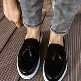 Black tassel loafers, front view with white sole and curved uppers